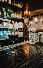 bartender pouring red wine into a glass in cafe or bar on the bar counter