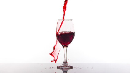 Red wine being poured into wine glass on white background.