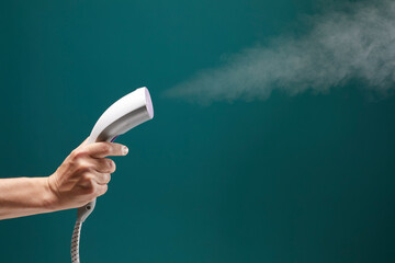 Close up view of male hand with vertical steamer isolated on green background.
