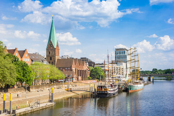 Historic sailing ships and church tower at the Weser river in Bremen, Germany