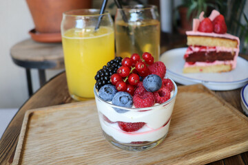 summer desserts with berries in a glass bowl and large glasses of homemade lemonade on a wooden  in a cafe
