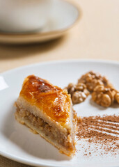 Traditional arabic dessert baklava and walnuts in white plate with a cup of coffee or tea  .Homemade baklava with nuts and honey.