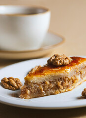 Traditional arabic dessert baklava and walnuts in white plate with a cup of coffee or tea  .Homemade baklava with nuts and honey.