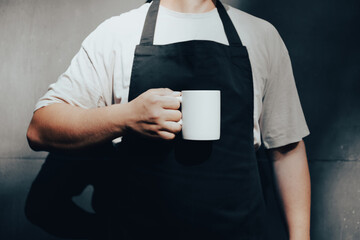 Man wearing apron holding mug of coffee mockup