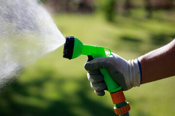 Gardener watering lawn with hose sprinkler