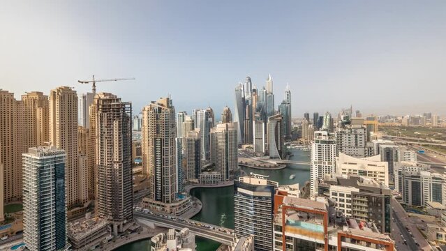 Panoramic view of various skyscrapers in tallest recidential block in Dubai Marina aerial timelapse with artificial canal. Many towers and yachts