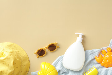 Baby sunscreen cream bottle with sunglasses, panama hat, towel, sand molds on beige table. Sun...