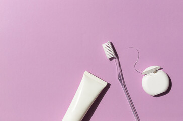 Dental care concept frame with toothbrush, tooth floss and toothpaste on the bright violet...
