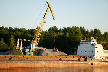 Floating crane in the river port on a summer day. The concept of export and import of goods