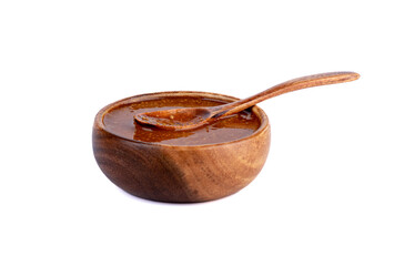 Wooden bowl with Bavarian mustard and a wooden spoon on a white background.