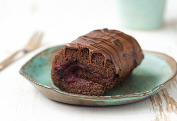 Chocolate cake with blackcurrant in ceramic plate on white wooden background.close up
