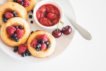 Homemade cottage cheese pancakes with fresh berries on white table