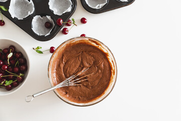 Cooking homemade cherry muffins with fresh berries on white wooden table. Top view
