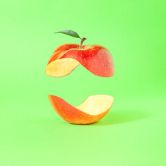 Minimal composition with levitating halved red apple against bright green background. Jin and jang concept. Balanced healthy diet idea. - obrazy, fototapety, plakaty