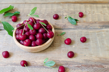 Many ripe red cherries in a wooden bowl on a wooden table. Healthy food concept. Horizontal orientation.