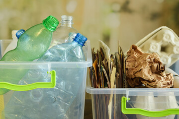Two containers filled with multicolored plastic bottles and wastepaper on blurred background....