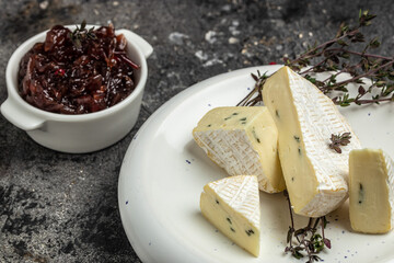 Brie cheese with a white and blue mold, camambert cheese on a wooden board. truffled brie cheese on...