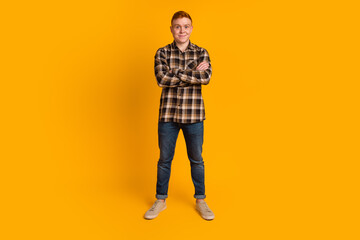 Portrait of a happy casual man stand with arms folded over yellow background isolated