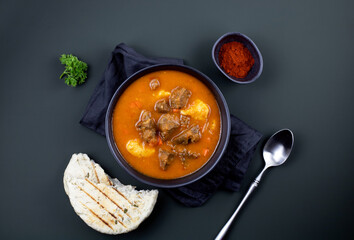 Hungarian goulash, top view. Stewed beef with potatoes, carrots, paprika, spices on a dark background, top view.