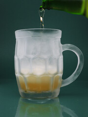 Pouring beer with bottles into a frozen glass ...