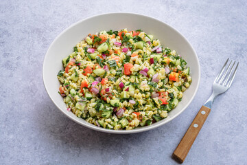 Tabbouleh salad with fresh herbs parsley, mint, bulgur, onion, diced cucumber, tomato, dressed with olive oil and lemon juice. Cold salad. Vegan healthy food concept 