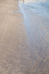 Sea tide waves, natural sand and water texture. Smooth sand background. Sandy beach wet surface, summer concept