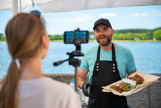 man chef gives an interview for a video blogger. videographer is filming the cook's story about cooking. outdoor
