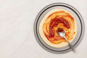 Preparing pizza on the table with ketchup on the top