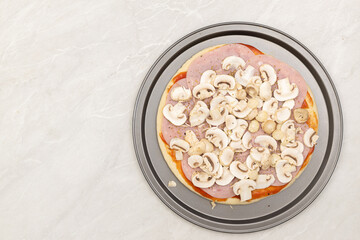 Raw pizza prepared for baking with ketchup ham mushrooms and cheese