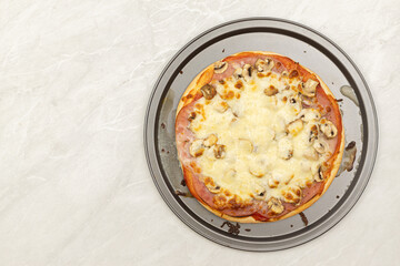 Top view of baked pizza with ketchup ham cheese and mushrooms