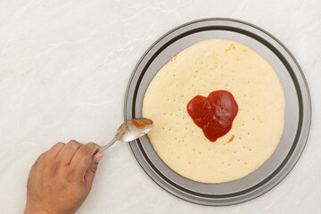 Preparing pizza on the table with ketchup on the top