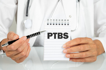 Ärztin zeigt auf einen Notizblock auf dem PTBS für Post Traumatische Belastungsstörung steht