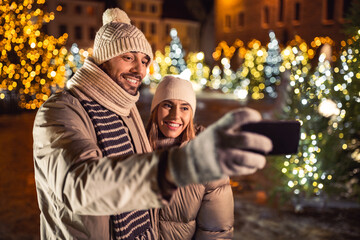 winter holidays and people concept - happy smiling couple taking selfie with smartphone over...