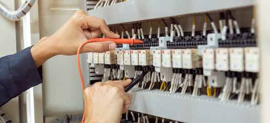 Electrical engineer using measuring equipment to checking electric current voltage at circuit breaker and cable wiring system , Electrical service concept .