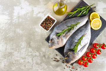 Fresh fish dorado and ingredients for cooking. Raw fish dorada with spices and herbs on gray concrete table. Seafood, restaurant, diet, healthy food background. Top view, flat lay with copy space