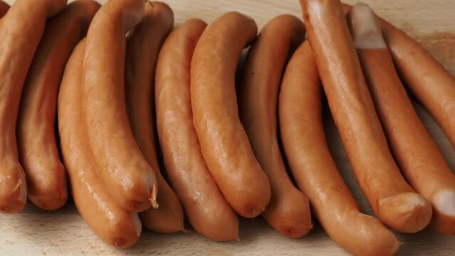 Thin long pork sausages on the wooden cutting board