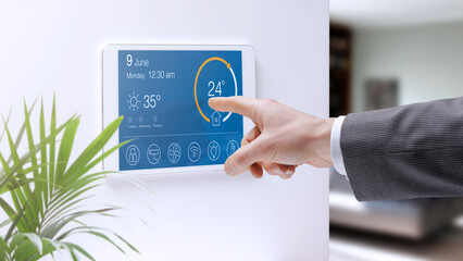 Man setting home temperature using a smart home system - obrazy, fototapety, plakaty