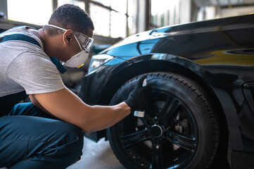 Fototapeta na wymiar Experienced auto detailer applying the tire gloss before car polishing