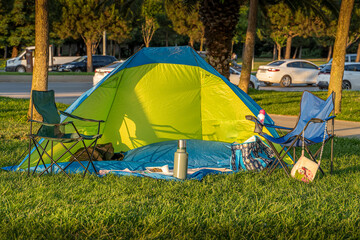 Camping tent with desk and chairs in a park.Camping equipments.