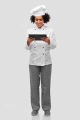 cooking, culinary and people concept - happy smiling female chef in toque and jacket with tablet pc computer over grey background