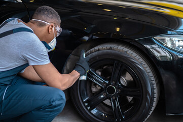 Naklejka na ściany i meble Service man coating the automobile tire with polish