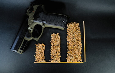 Gun and grains of wheat in the form of pillars of the chart on a black background.