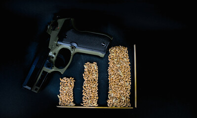 Gun and grains of wheat in the form of pillars of the chart on a black background.