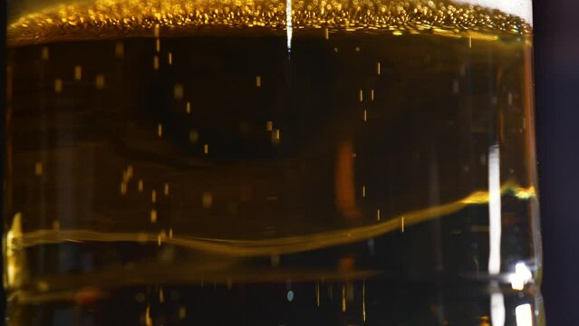 Beer bubbles rising to the top of a glass close up view.