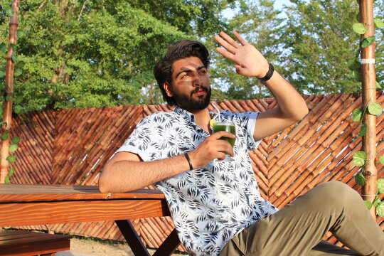 Young man sitting in a restaurant outdoor sitting place enjoying mint margarita in hot weather
