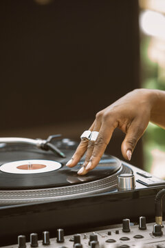 Close up view of the hand of a black woman deejay while mixing a vinyl in a turntable