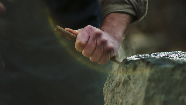 Sculptor shaping a big stone. Rock breaking