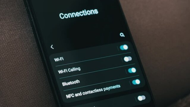 Turning on Wi-Fi on a smartphone. The wifi button is turned on the mobile phone in the connections menu. Male finger hand touching touchscreen on modern smart phone with wi fi zone on screen.