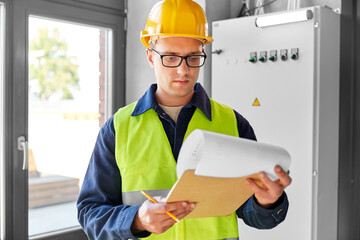 construction business and building concept - male electrician or worker in helmet and safety west...