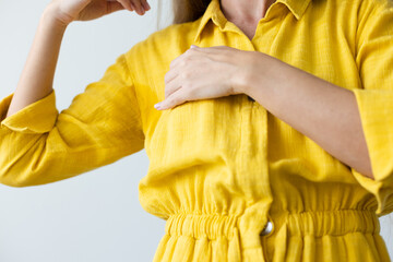 Woman in yellow dress with wet armpits. Closeup.